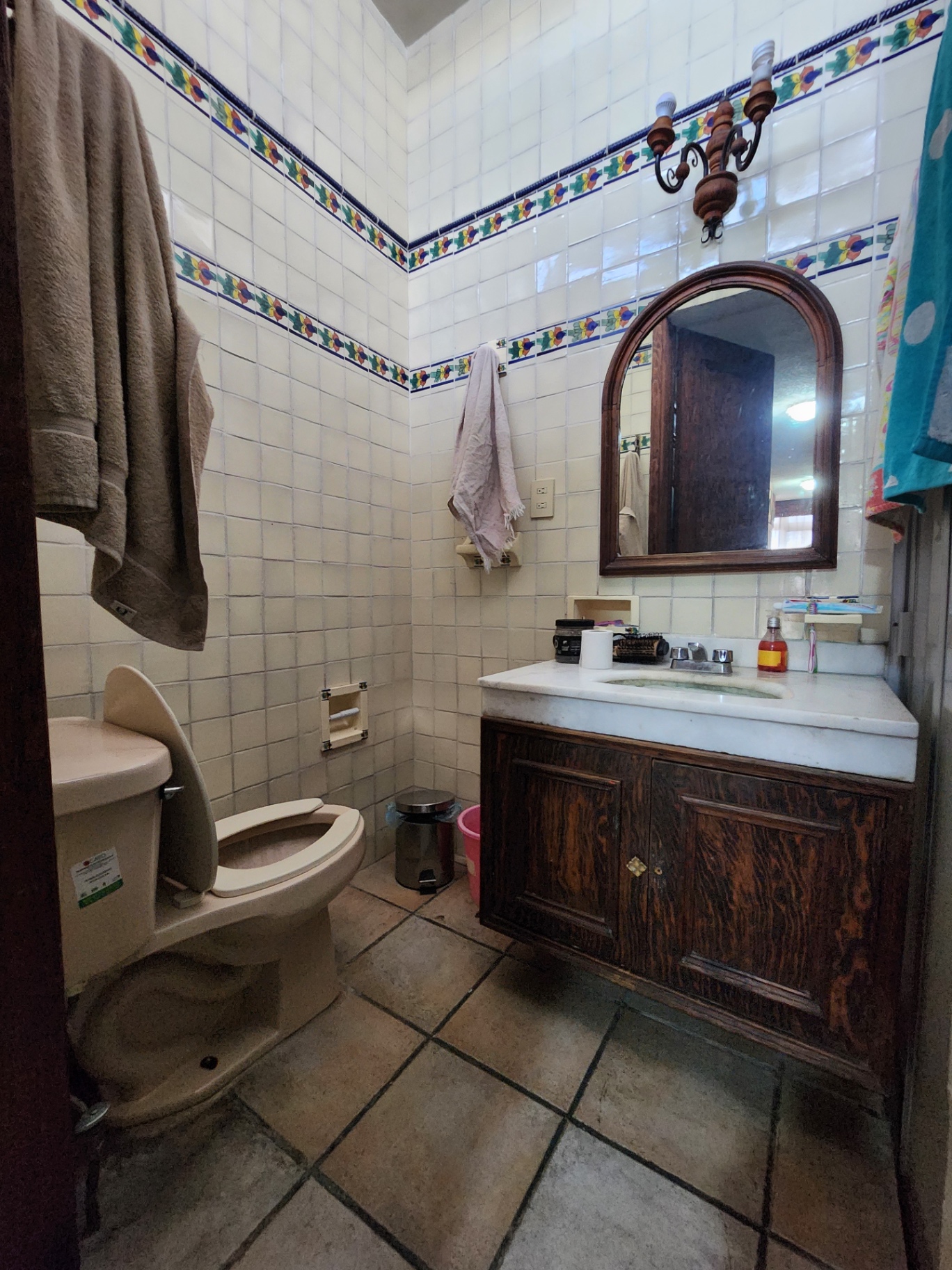 Baño con acabados en talavera, cubierta de mármol y mueble de madera