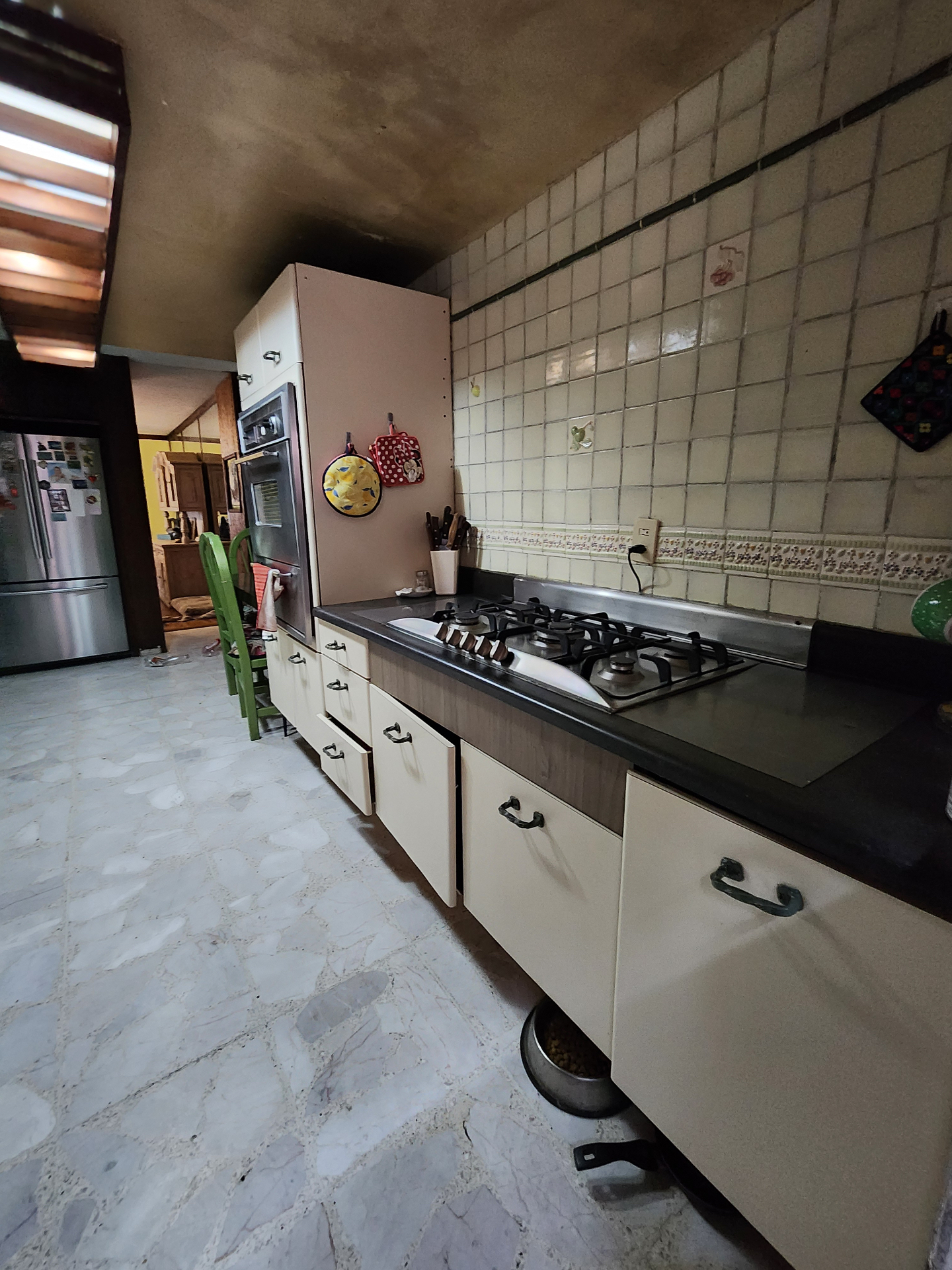 Cocina principal con cubierta oscura, alacenas lineales y muro cerámico