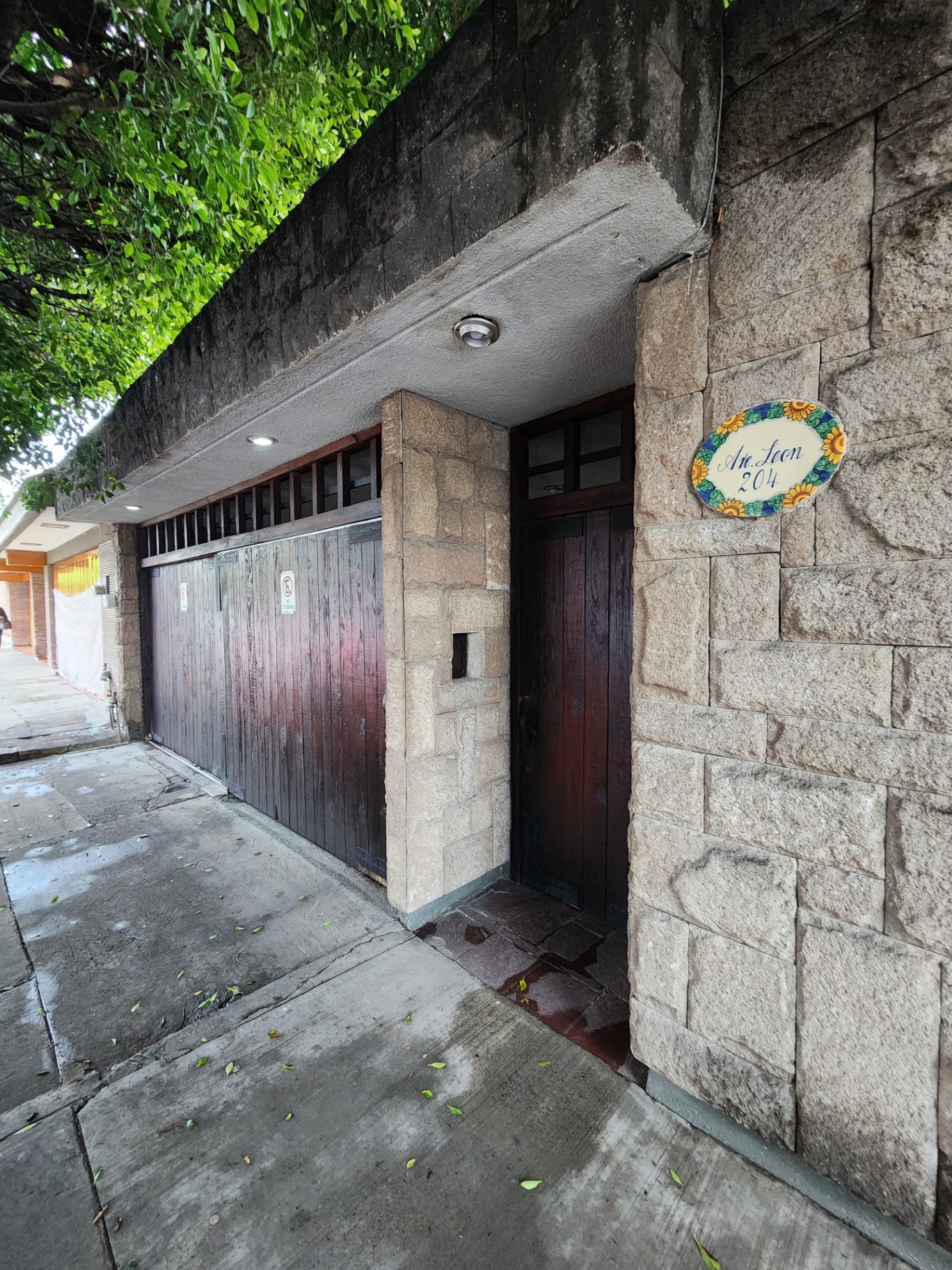 Acceso peatonal con muro de cantera y puerta de madera