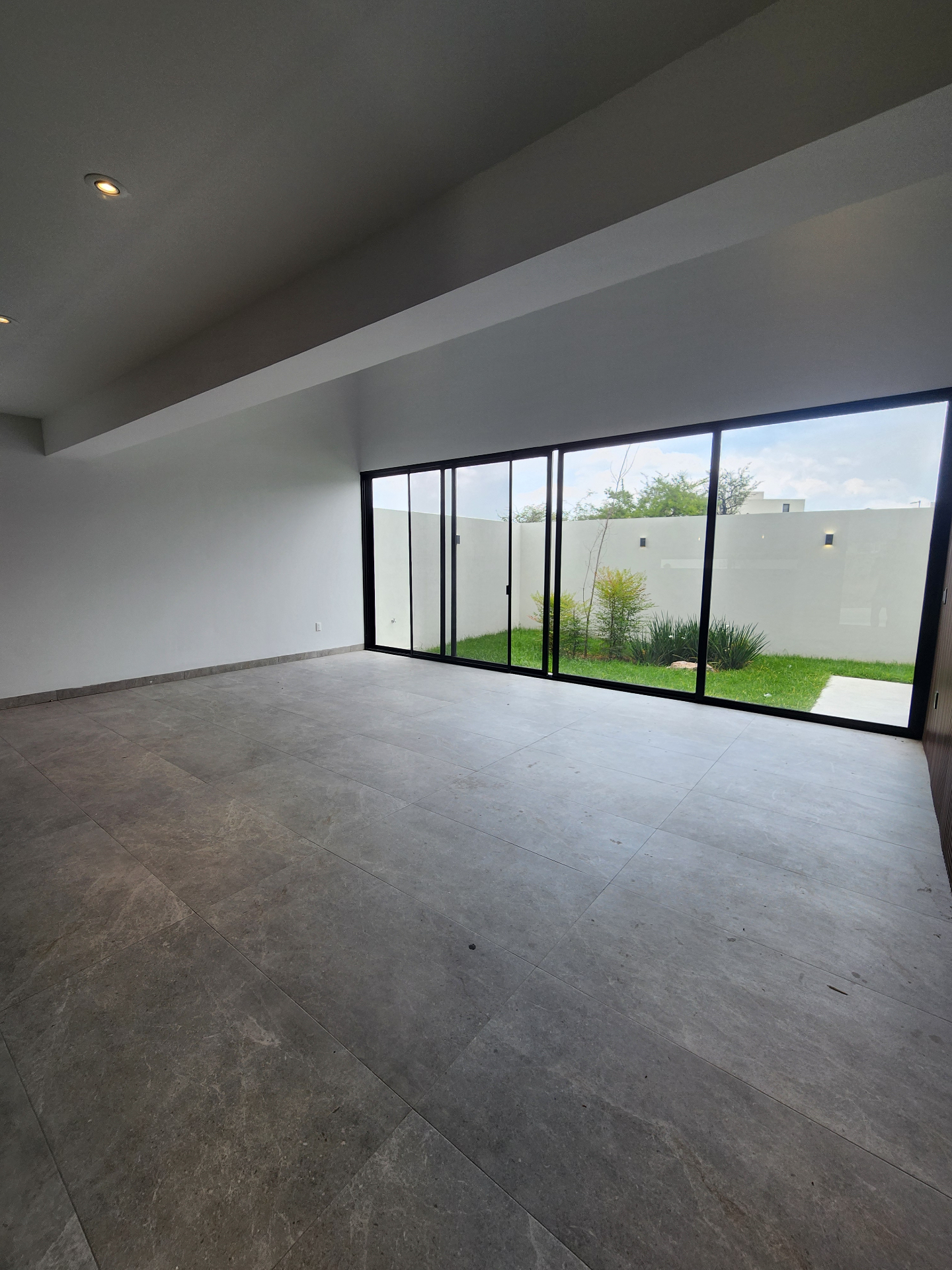 Sala–comedor a doble altura con ventanal corredizo al jardín