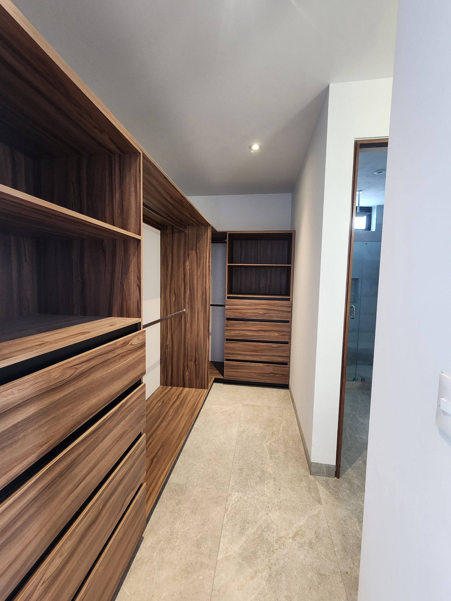 Vestidor en madera con cajonería y acceso al baño principal