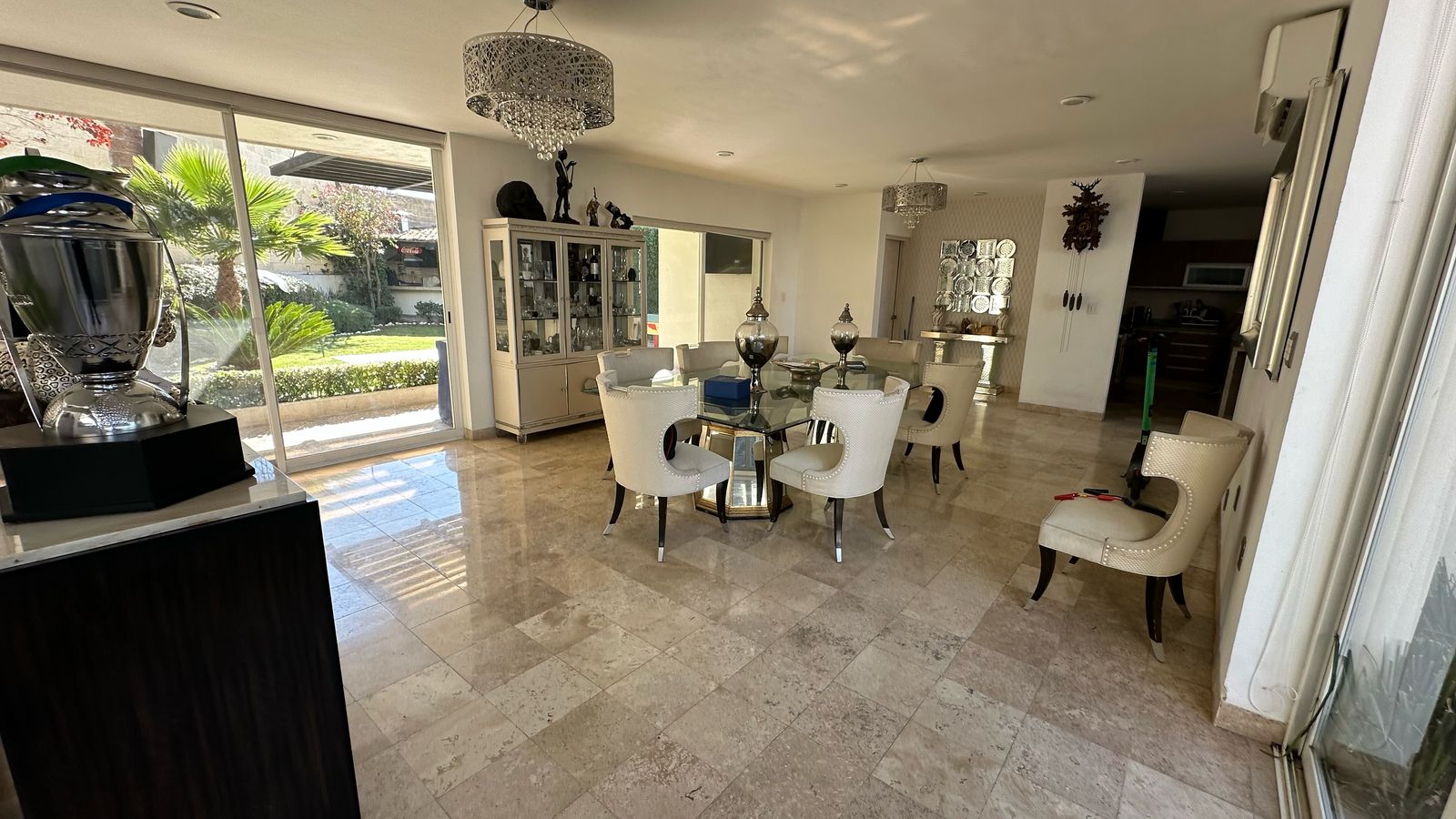 Comedor principal con candiles dobles, ventanales hacia el jardín y pisos de mármol