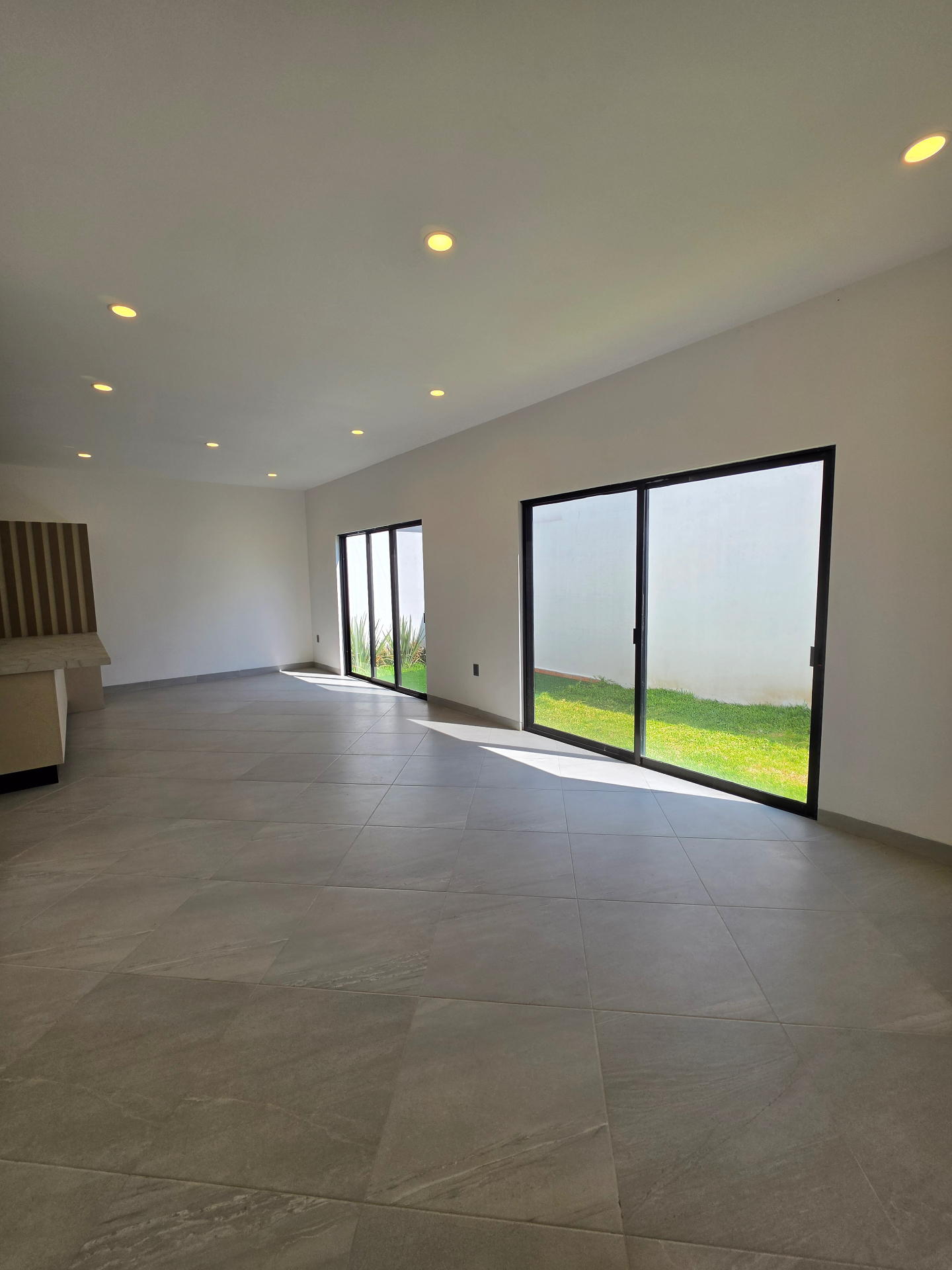Sala y comedor con ventanales corredizos de piso a techo y jardín lateral