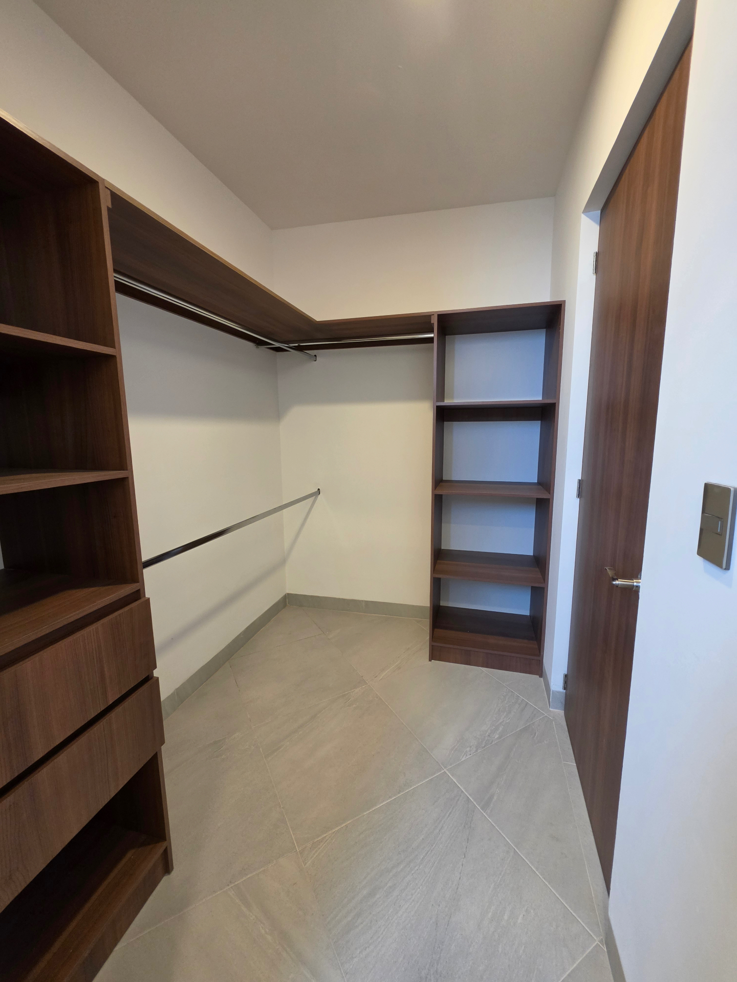 Vestidor abierto con carpintería en madera, cajoneras y repisas laterales