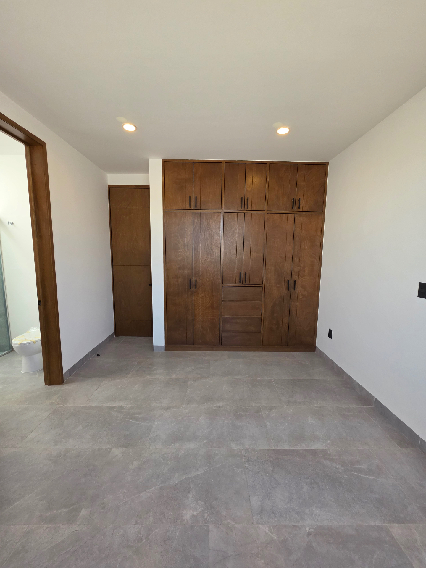 Habitación con clóset de madera empotrado de piso a techo y acceso a baño completo