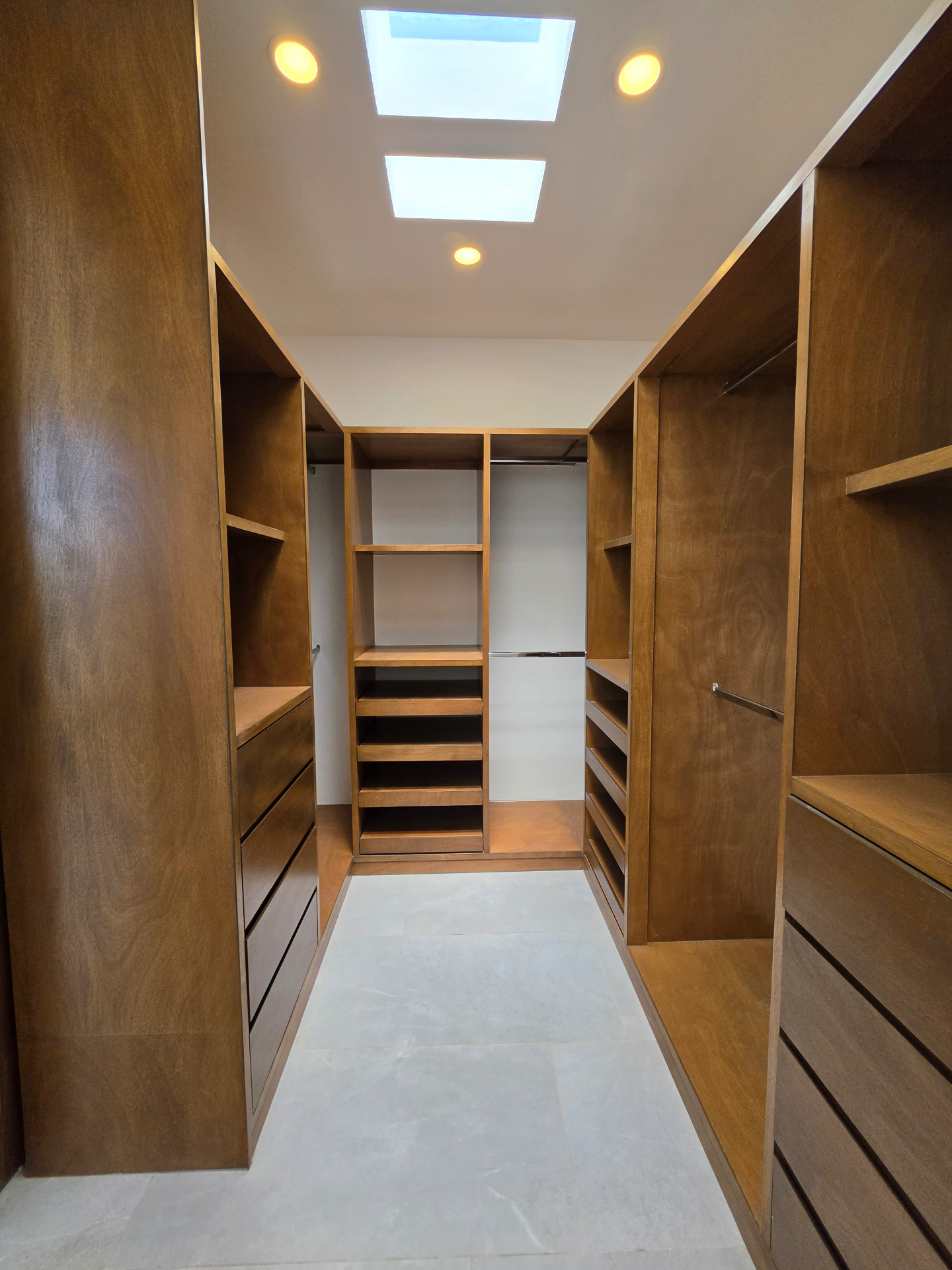 Vestidor amplio con carpintería en madera, cajoneras, entrepaños y tragaluces cenitales